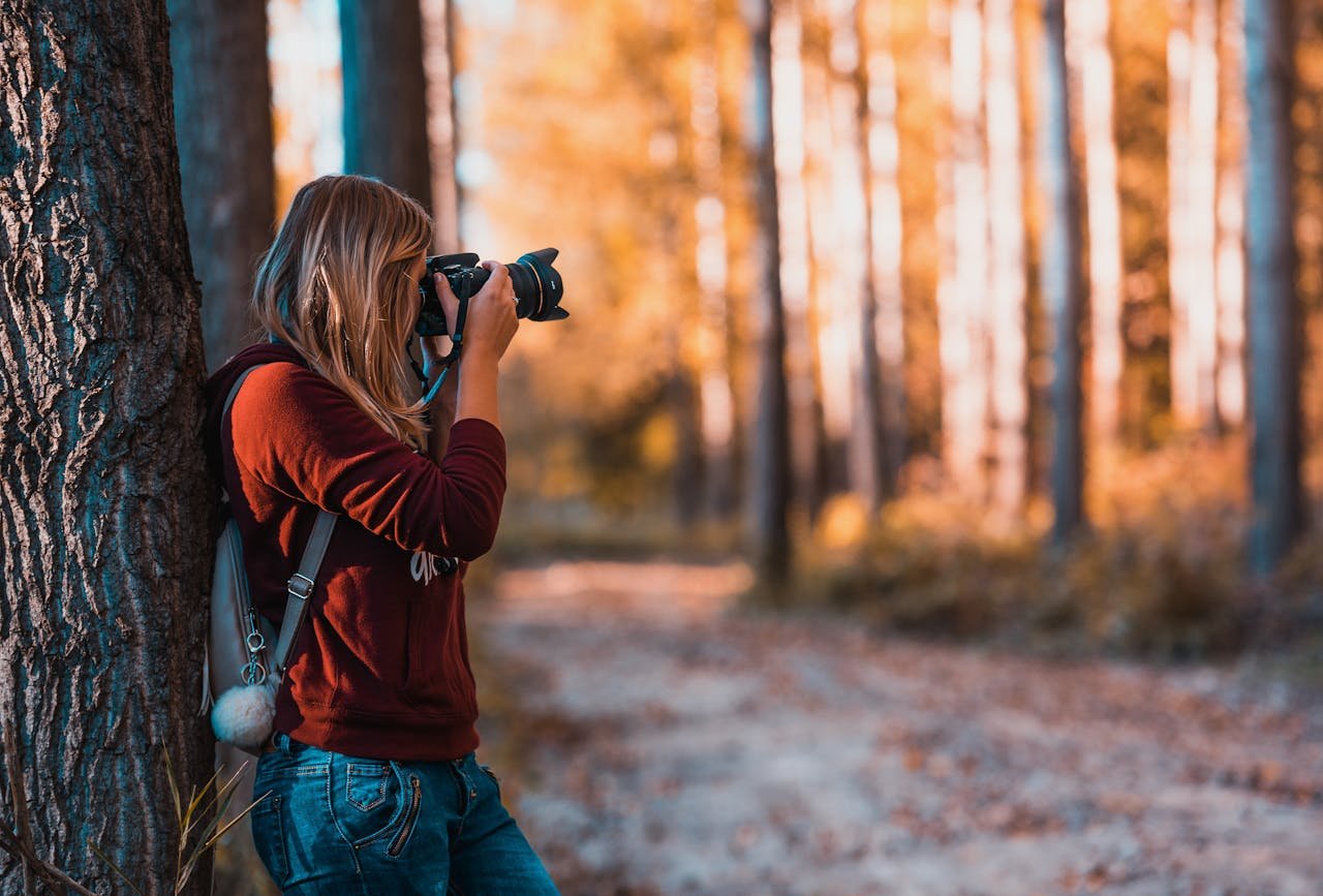 about-01 A woman taking photos in an autumn forest, perfectly capturing the beauty of nature.